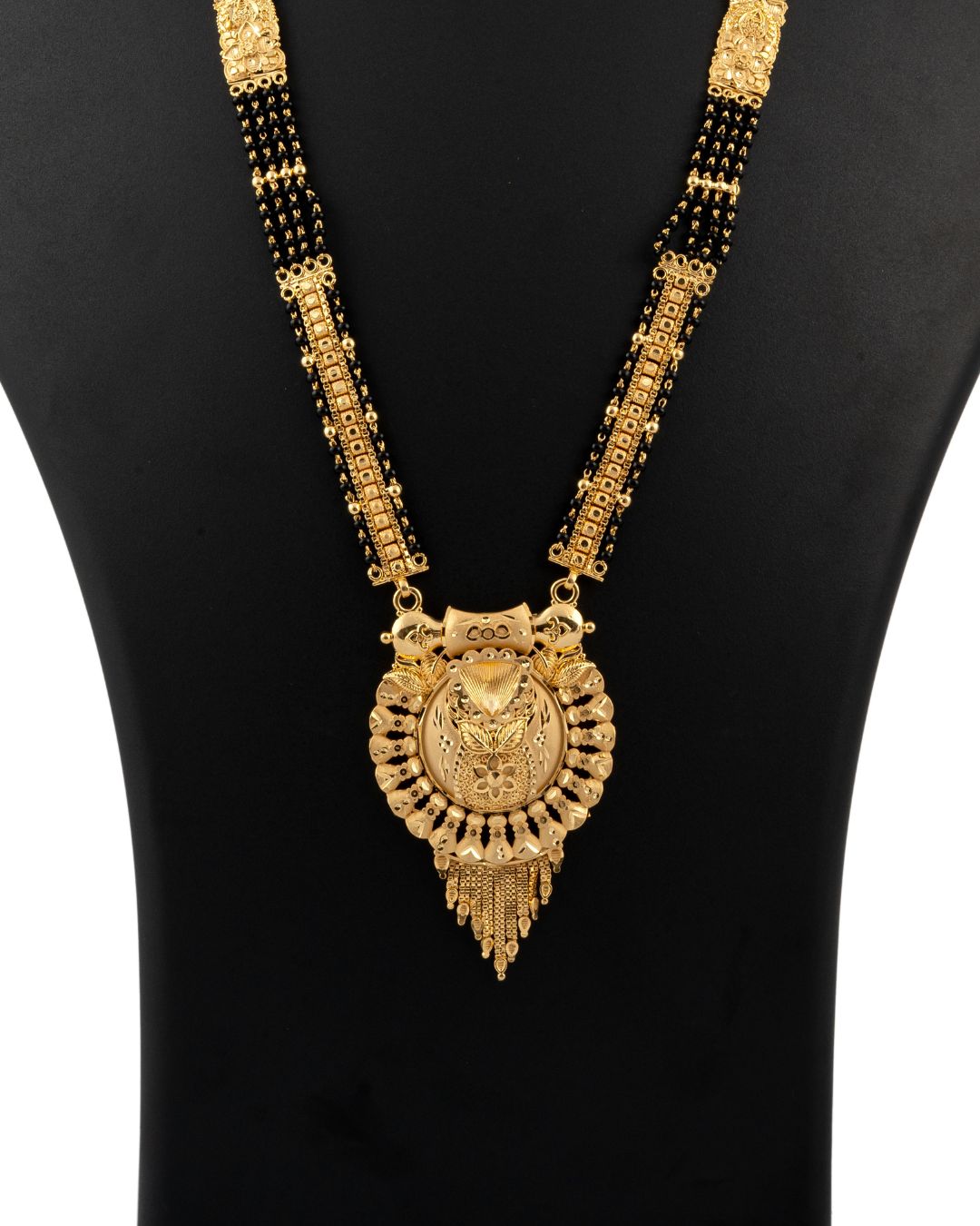 Gold necklace with a large pendant on a black background