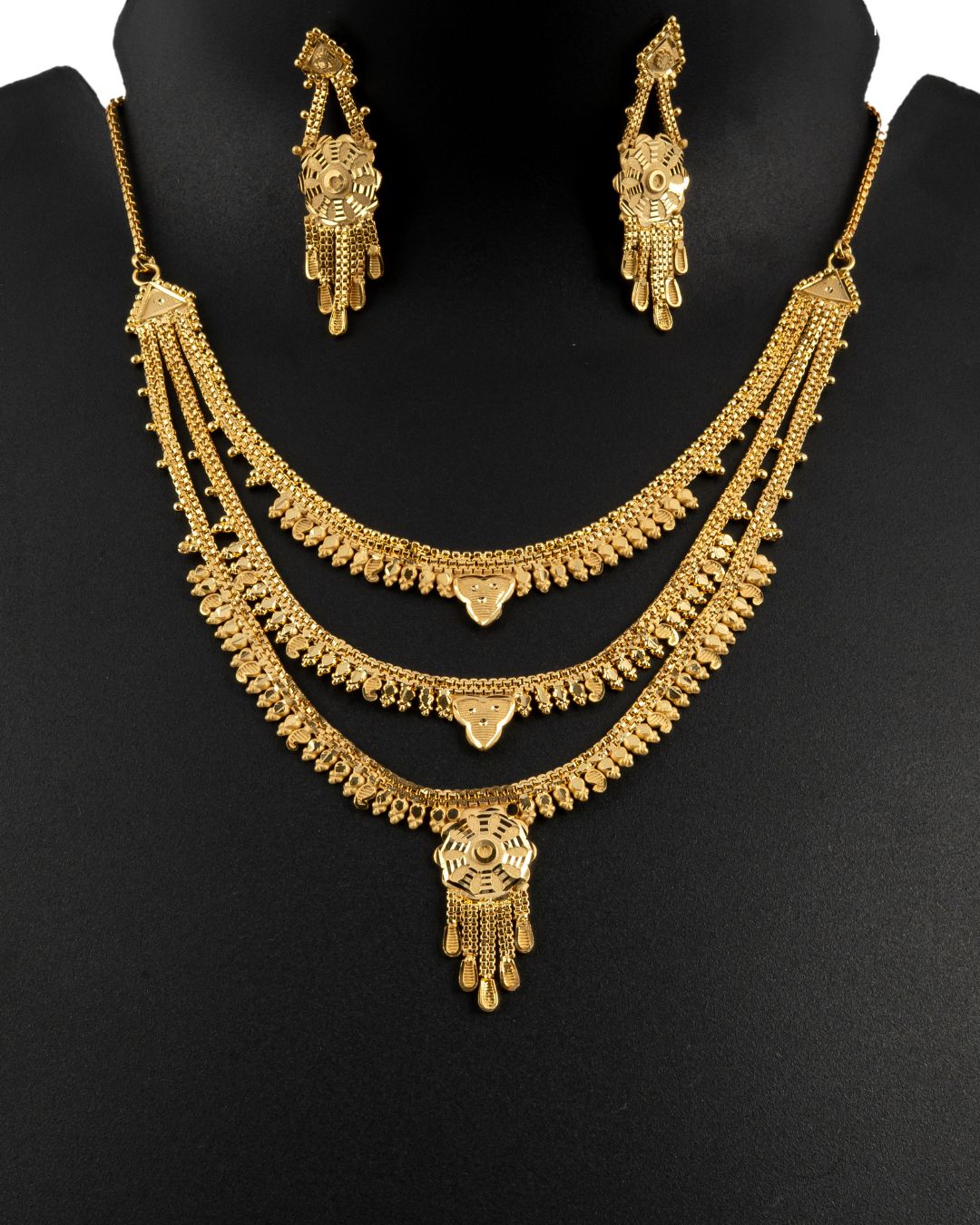 Gold necklace and earrings set on a black background