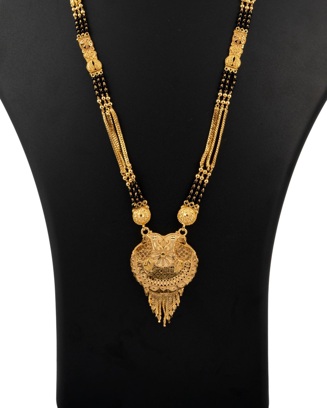 Gold necklace with black beads on a black mannequin