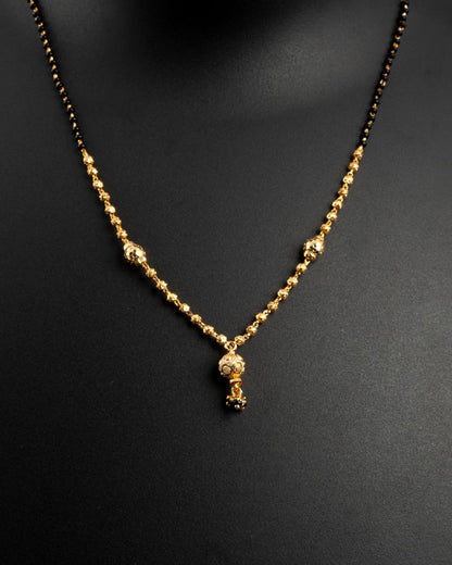 Gold necklace with a small pendant on a black background