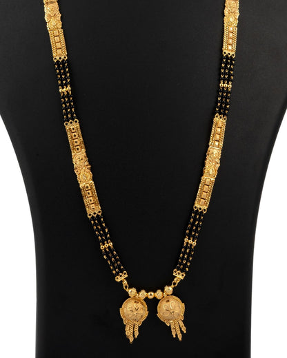 Gold and black necklace on a mannequin with a plain background