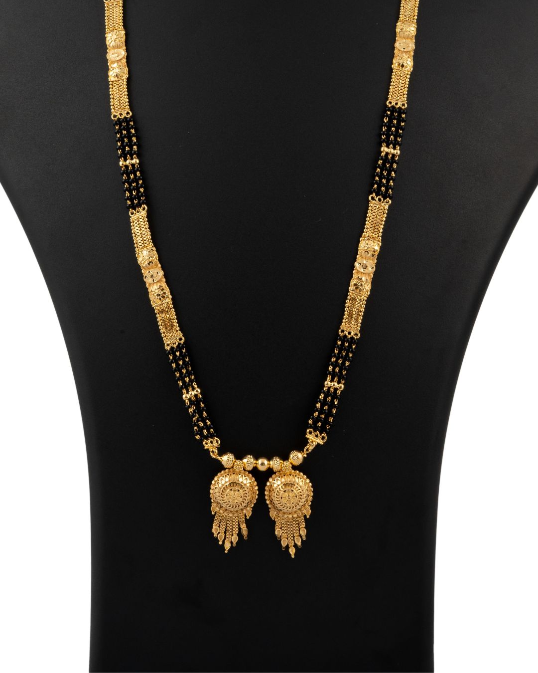 Gold necklace with black beads on a black mannequin