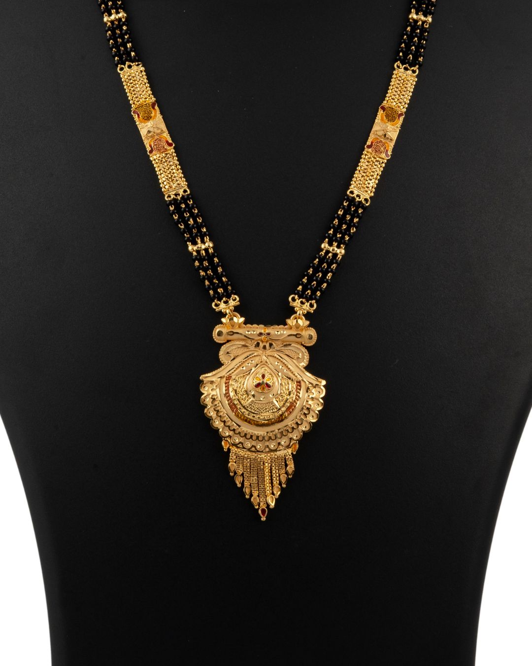 Gold necklace with black beads on a black background