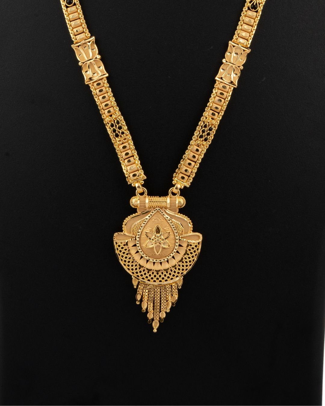 Gold necklace with a detailed pendant on a black background