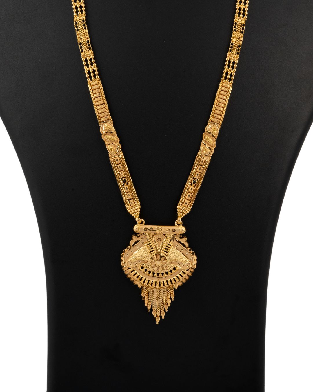 Gold necklace with a large pendant on a black background