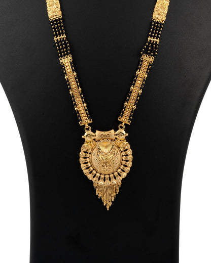 Gold necklace with a large pendant on a black background