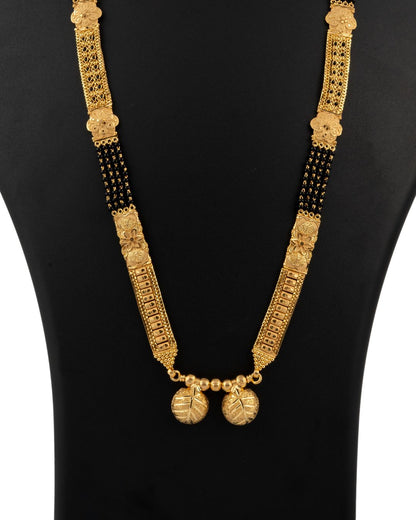 Gold necklace with black beads on a black mannequin