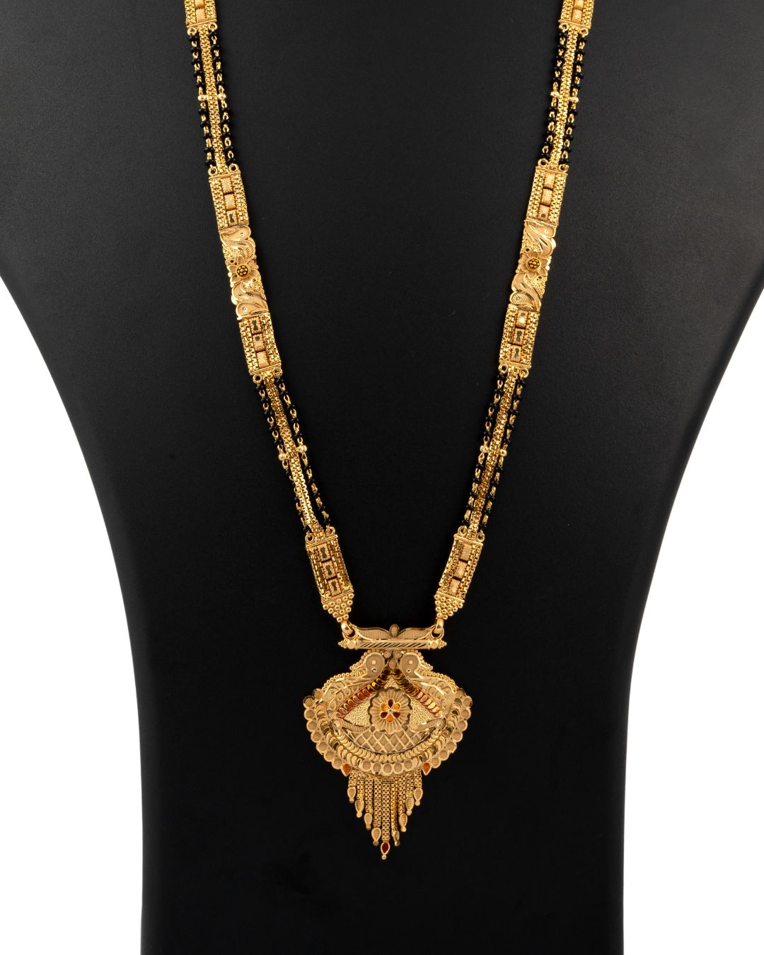 Gold necklace with intricate design on a black mannequin