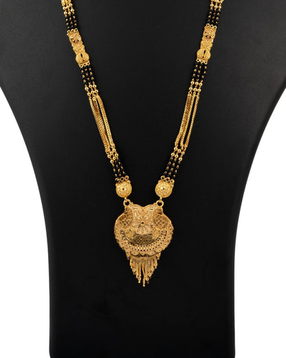 Gold necklace with black beads on a black mannequin