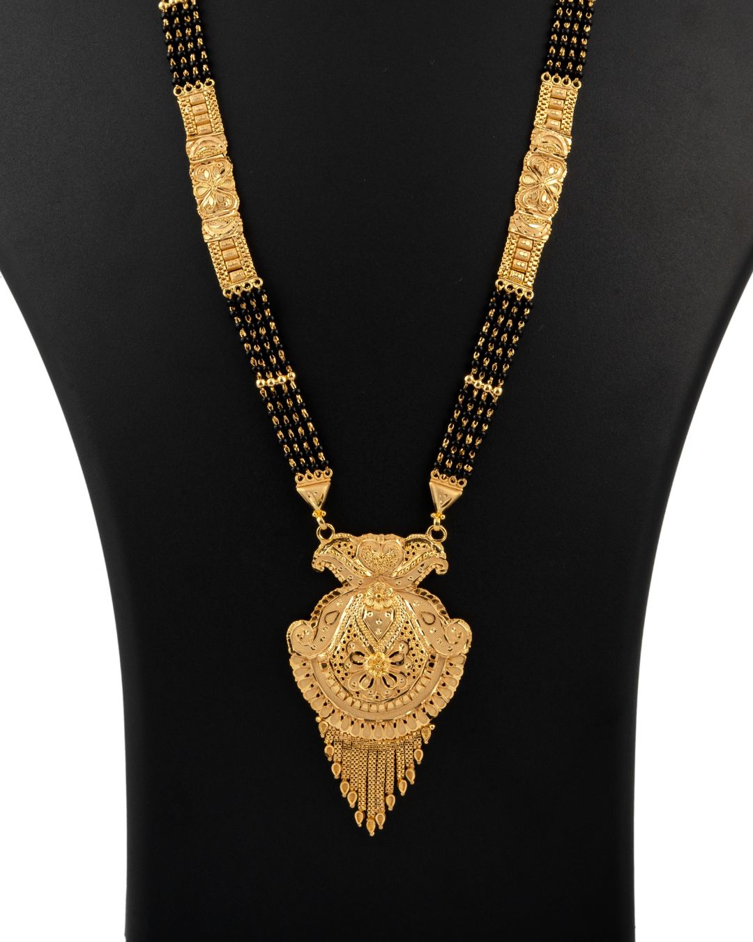 Gold necklace with a large pendant on a black mannequin