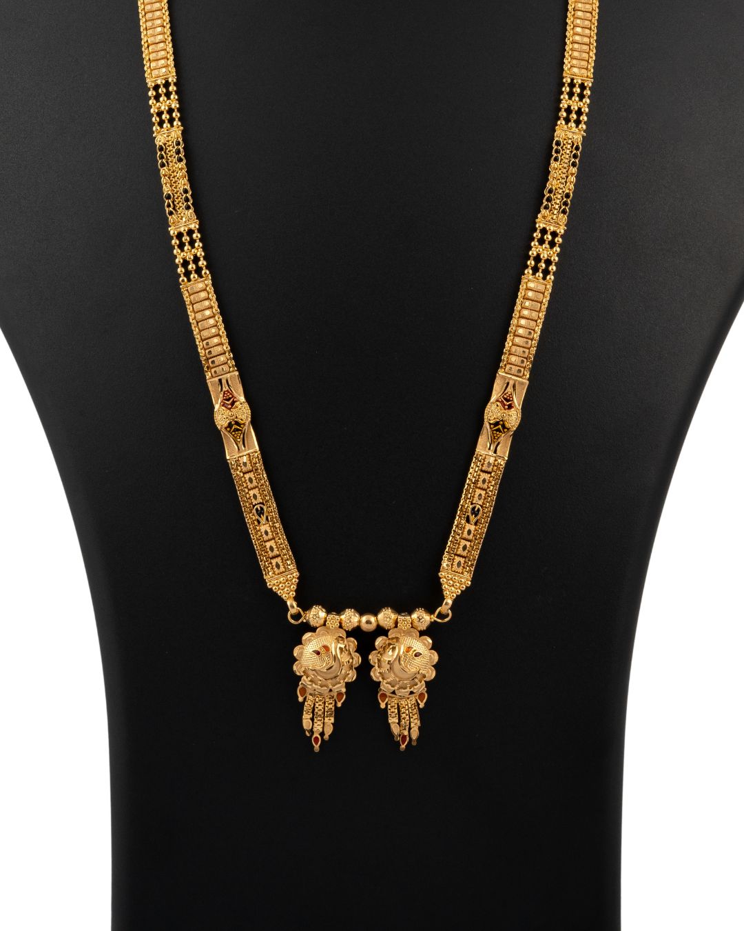 Gold necklace with intricate design on a black mannequin
