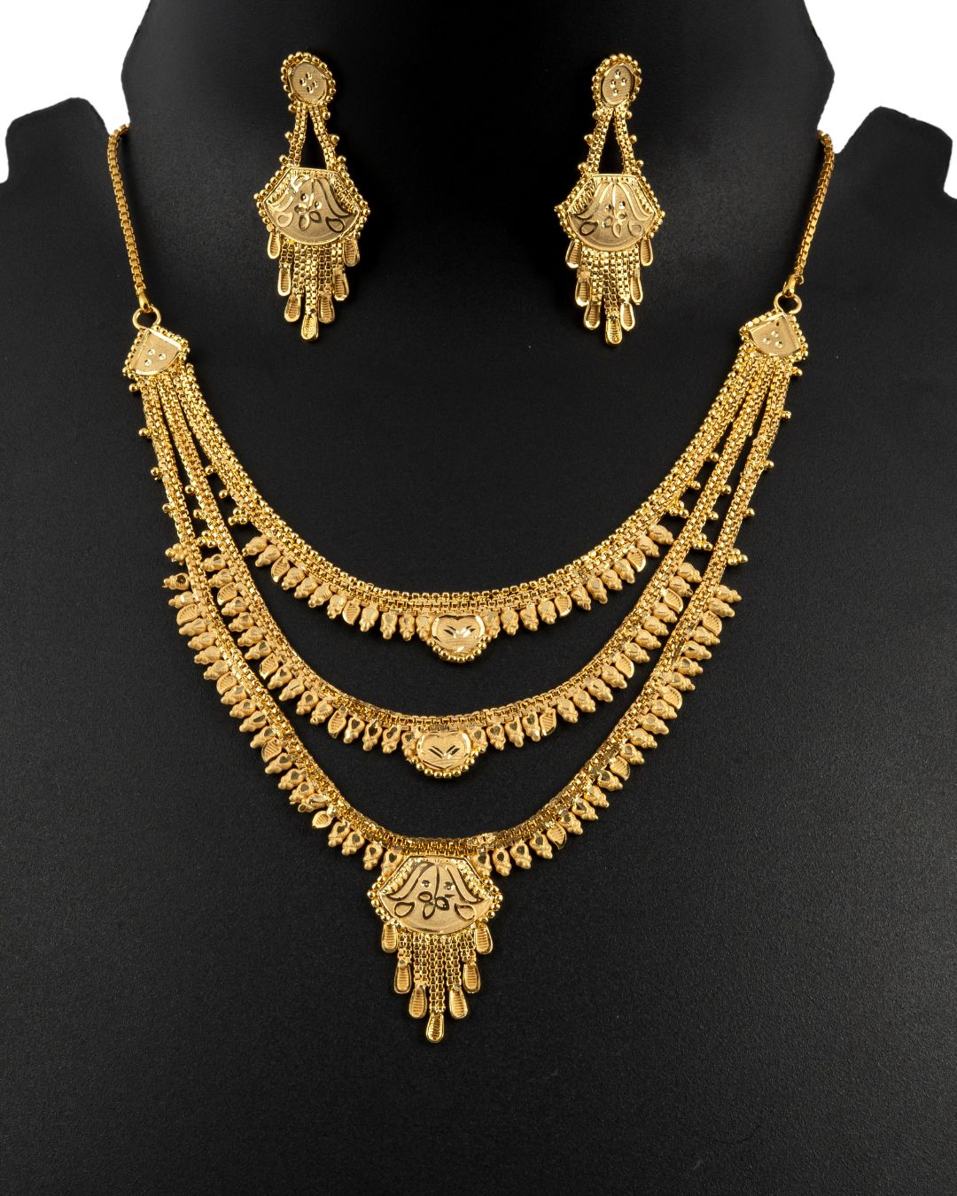 Gold necklace and earrings set on a black mannequin