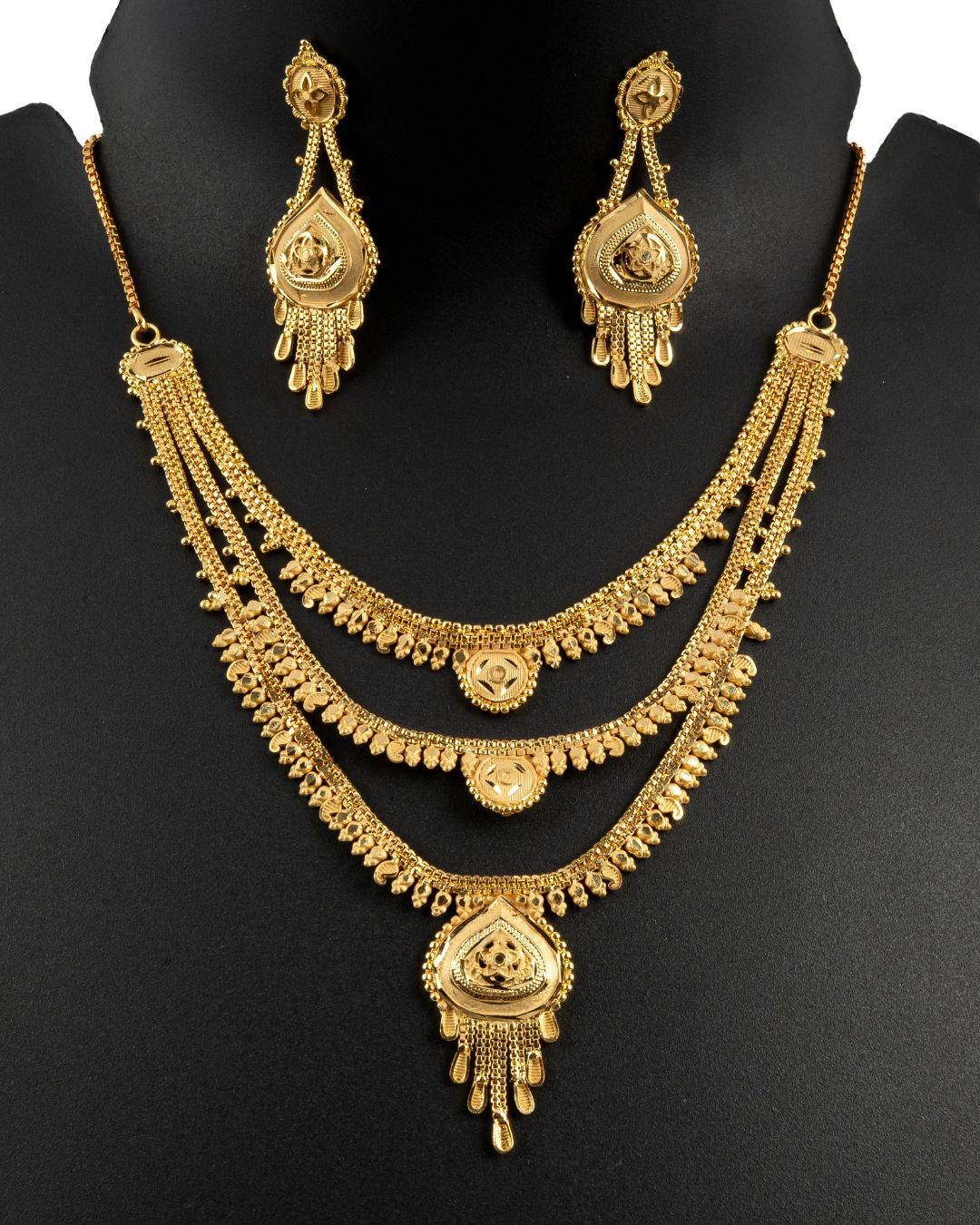 Gold necklace and earrings set on a black mannequin