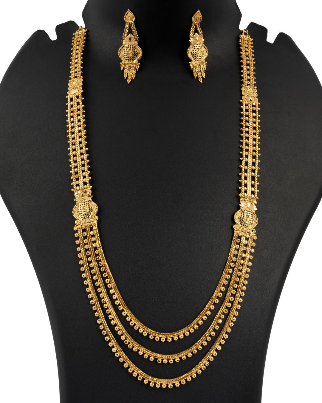 Gold necklace and earrings set on a black mannequin